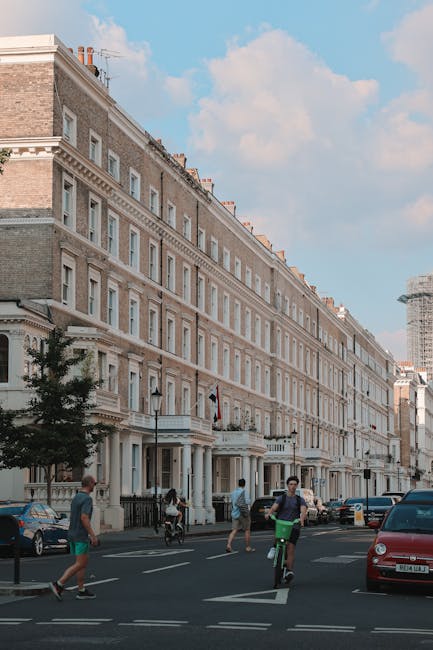 A row of colorful terraced houses in South Kensington, featuring pastel-colored facades including light blue, yellow, and lavender. Each house has white-framed sash windows and black wrought iron rail